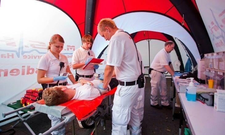 Emergency personnel care for a patient inside an inflatable medical tent.