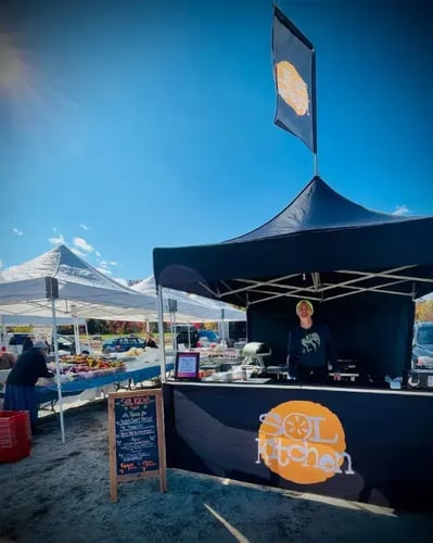 A 10x10 heavy-duty pop-up tent with full, half walls and countertops used for food sales at farm markets.