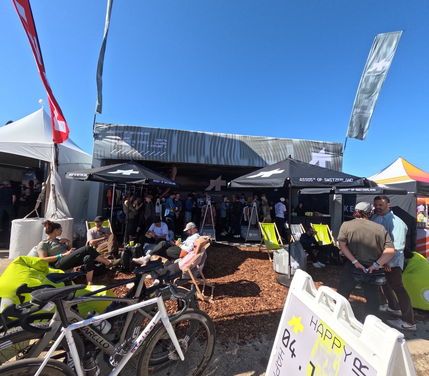 Assos Custom Truss With Flags and Umbrellas Plus Seating for Guests and Happy Hour