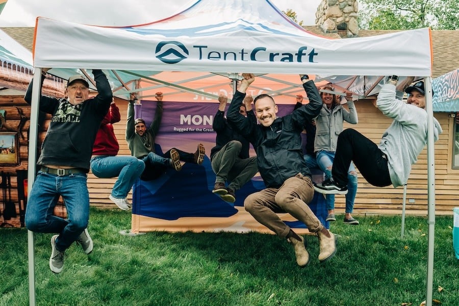 TentCraft employees hang from a heavy-duty MONARCHTENT pop-up tent