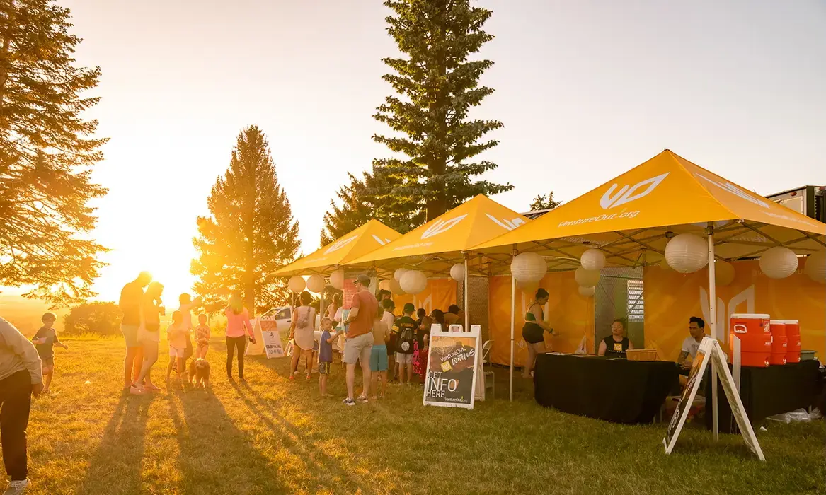 MONARCHREACH set up at a community event with a sunset in the background