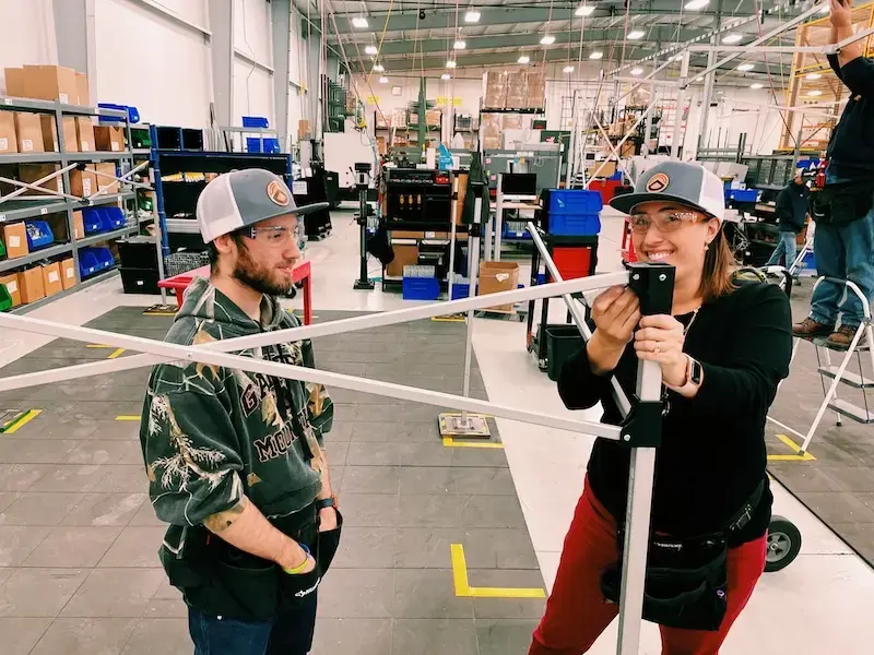 A pair of TentCraft employees construct a custom pop-up tent frame