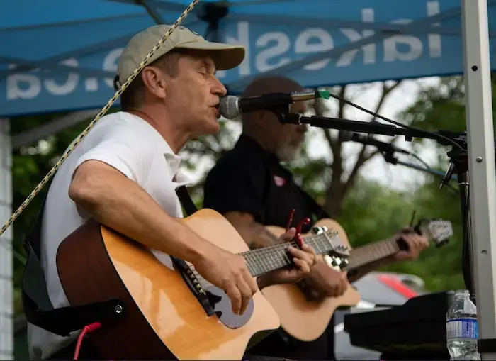 A guitar player sings under a mightyTENT