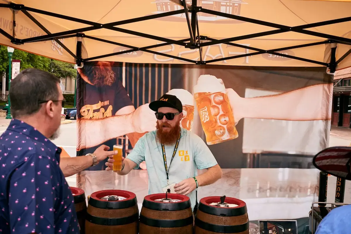 A bartender serves up a beer from under a Fass Brewing pop-up tent