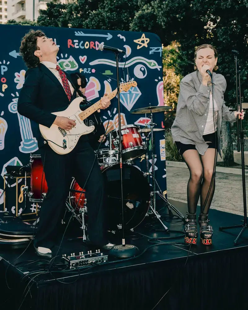 Performers in front of a Greater Than Distribution backdrop