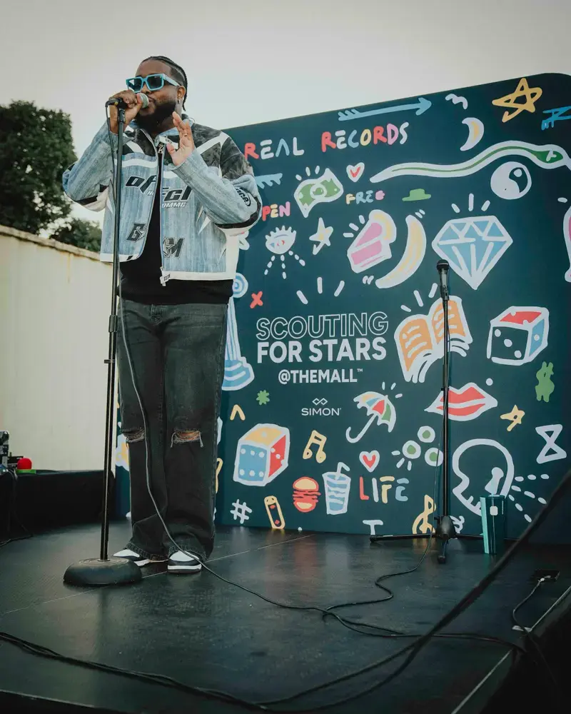 A performer in front of a Greater Than Distribution backdrop