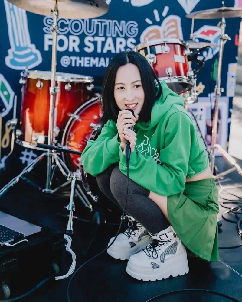 A Performer in front of a Greater Than Distribution backdrop