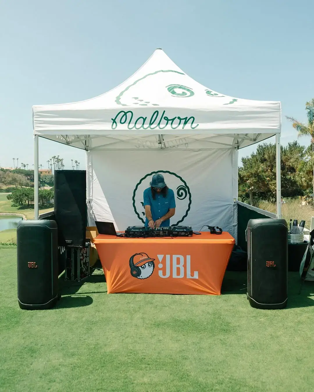 A DJ spins music under a Malbon Golf tent