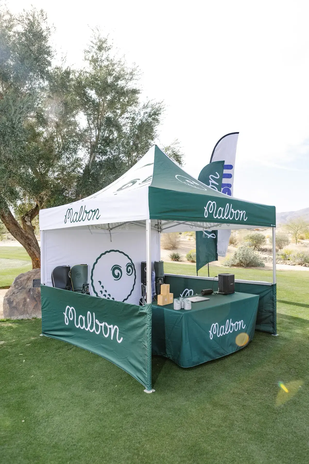 10x10 custom pop up tent for Malbon golf with side walls, table cover, and a flag